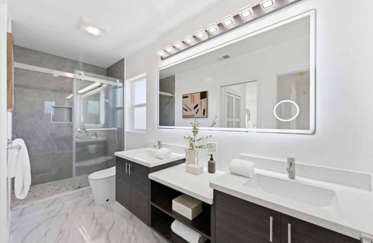 Contemporary bathroom with illuminated mirror, double vanity and stone shower