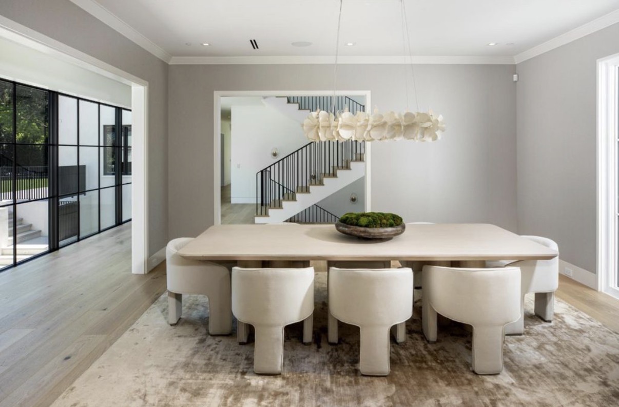 Formal dining room with sculptural lighting and custom staircase beyond