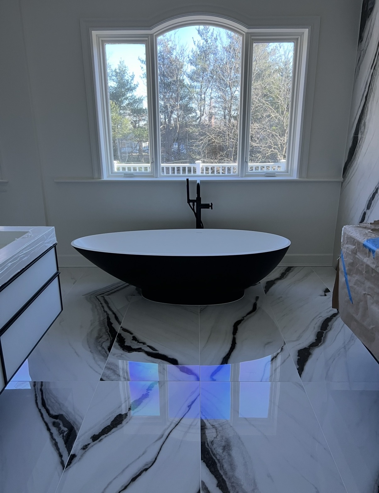 Renovated primary bathroom with freestanding tub and bookmatched stone flooring