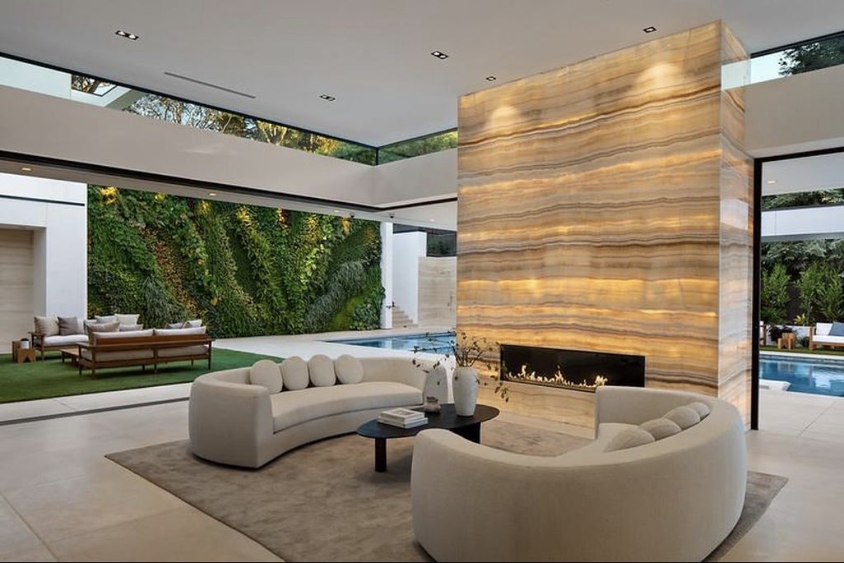 Open luxury living room with illuminated stone fireplace and garden views