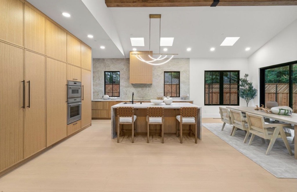 Expansive oak kitchen and dining space with custom cabinetry and stone island