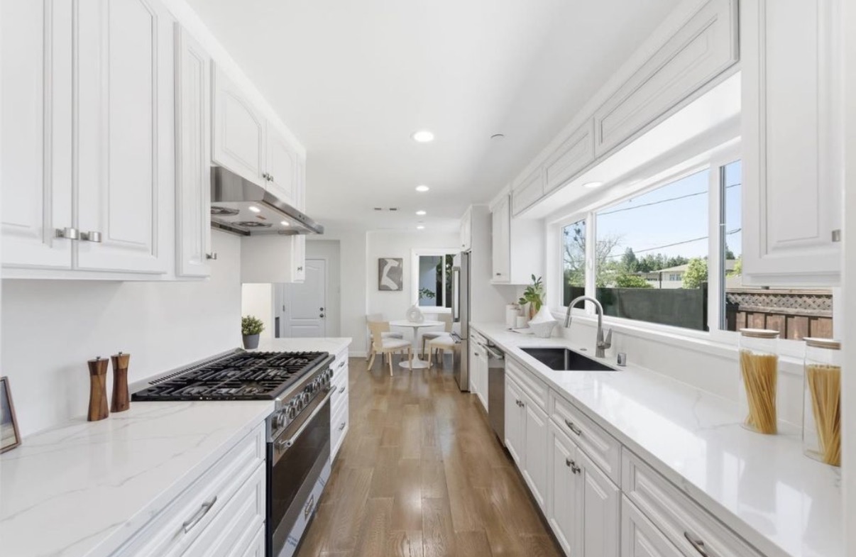 Bright custom white kitchen with professional range and garden-facing windows