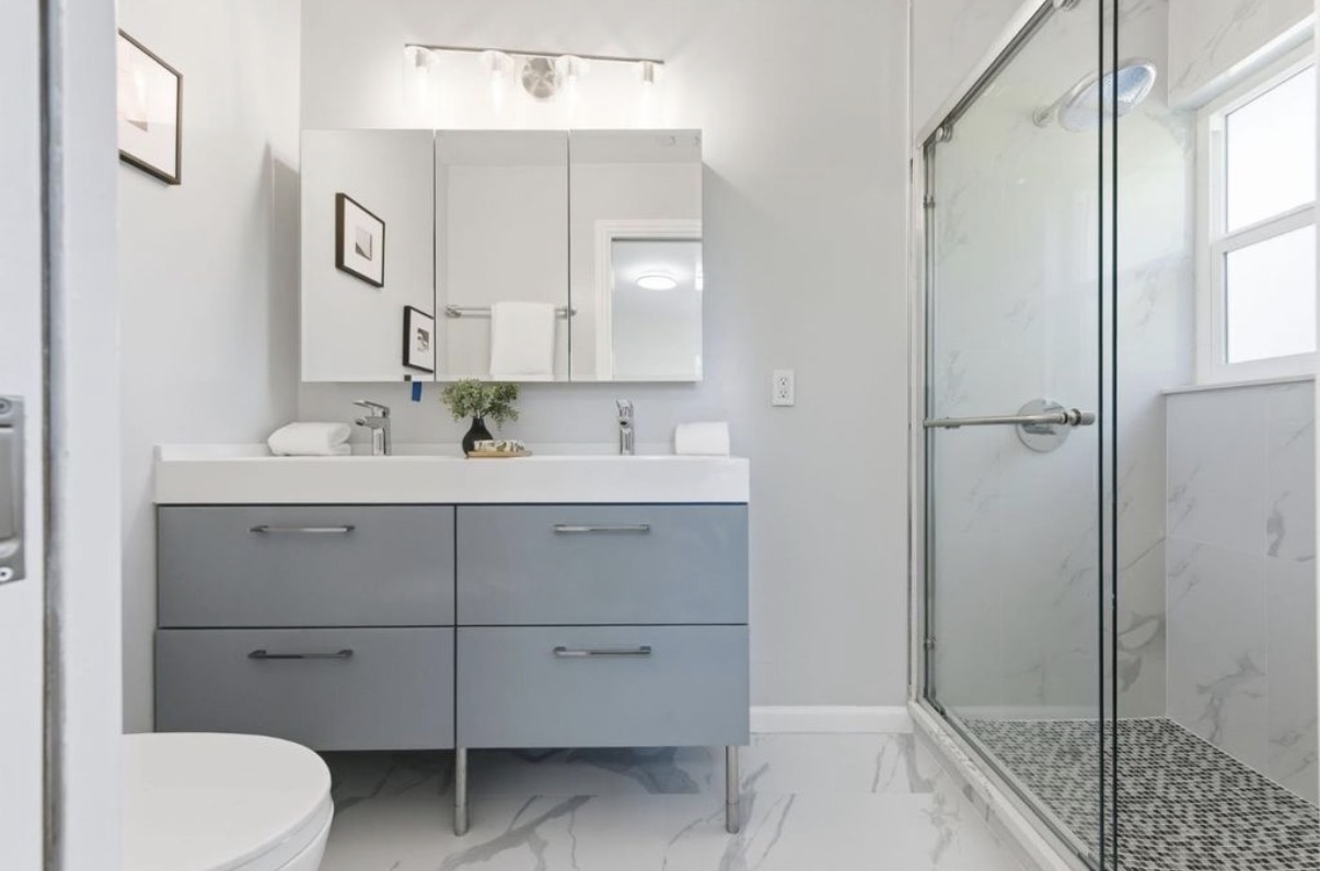 Modern double-vanity bathroom with glass shower and marble-look flooring