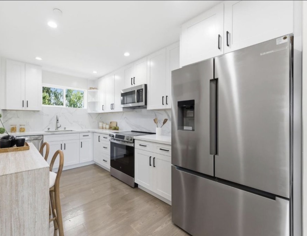 Crisp white kitchen with stainless steel appliances and black hardware