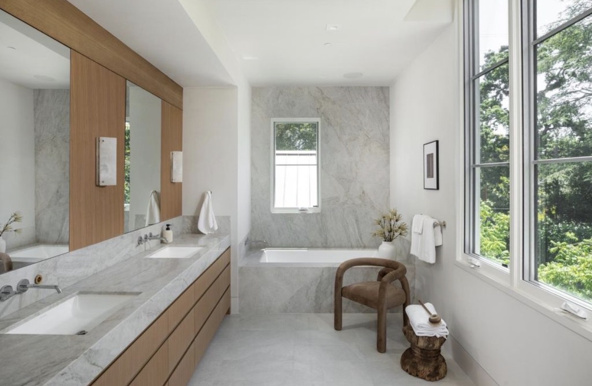 Light-filled primary bathroom with custom oak vanity and stone soaking tub